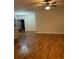 Bright living room featuring hardwood flooring, a ceiling fan, and large windows offering natural light at 2423 Turnbury Glen Walk, Snellville, GA 30078