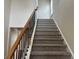 Staircase featuring carpeted steps, a stained wood handrail, and black iron spindles, providing a stylish transition at 2423 Turnbury Glen Walk, Snellville, GA 30078