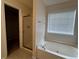 Bathroom with a soaking tub under a window and a glass door shower, plus tile floors and a large walk-in closet at 11800 Carriage Park Ln, Johns Creek, GA 30097