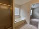 Bright bathroom featuring a soaking tub with window, glass-enclosed shower, and neutral tile flooring at 11800 Carriage Park Ln, Johns Creek, GA 30097