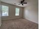 Bedroom featuring two windows for natural light, a ceiling fan and neutral carpeted floors at 11800 Carriage Park Ln, Johns Creek, GA 30097