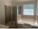Bathroom with a tiled shower and soaking tub near a window at 2118 Water Mill Ct, Buford, GA 30519