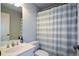 Cozy bathroom with gray striped shower curtain, white vanity, and chrome fixtures at 700 Broadlands Ln, Powder Springs, GA 30127