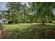 Large grassy backyard with plenty of shade from mature trees on a sunny day at 7144 Carolyn Cir, Lithia Springs, GA 30122