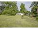 A large, sloping green backyard with mature trees and a view of the back of the house at 7144 Carolyn Cir, Lithia Springs, GA 30122