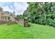 Lush backyard with green grass, a stone wall, and mature trees, offering a serene and private outdoor space at 8230 Royal Melbourne Way, Duluth, GA 30097