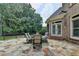 Backyard stone patio featuring an outdoor dining set and lush green landscaping, great for entertaining and relaxation at 8230 Royal Melbourne Way, Duluth, GA 30097