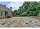Large stone backyard patio with mature trees, offering ample space for outdoor entertaining at 8230 Royal Melbourne Way, Duluth, GA 30097