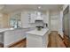 Bright kitchen features white cabinets, marble counters, modern appliances, an island, and hardwood floors at 8230 Royal Melbourne Way, Duluth, GA 30097