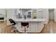 Bright kitchen features white cabinets, marble counters, an island, and modern appliances with hardwood floors at 8230 Royal Melbourne Way, Duluth, GA 30097