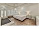 Luxurious bedroom with tray ceiling, hardwood floors, shutters, and sitting area at 8230 Royal Melbourne Way, Duluth, GA 30097
