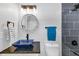 Modern bathroom featuring a blue vessel sink, granite counter, a round mirror, vanity, and stylish tiled tub and shower at 851 Flagler Se Cir, Smyrna, GA 30080