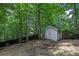 Exterior image of backyard shed featuring a gray facade, small wooden ramp, and wooded scenery at 131 Banyon Ct, Dallas, GA 30157