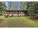 The home's backyard is a green space surrounded by mature trees, brick and stone exterior of the home at 1206 Tuckawanna Sw Dr, Atlanta, GA 30311
