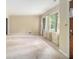 An empty living room with carpet flooring, several windows covered with lacey white curtains, and a tan paint scheme at 1206 Tuckawanna Sw Dr, Atlanta, GA 30311