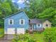 Quaint two-story blue home with white trim, a two-car garage, and a stone accented side entrance at 2419 Anderson Mill Rd, Austell, GA 30106