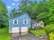 Quaint two-story blue home with white trim, a two-car garage, stone accents, and lush greenery at 2419 Anderson Mill Rd, Austell, GA 30106