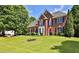 Beautiful two-story brick home with a lush green lawn and mature trees in a suburban setting at 3520 Mystic Dr, Buford, GA 30519
