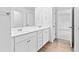 Bright bathroom featuring a double vanity with white cabinets, wood-look flooring, and a large mirror at 3660 Cattle Field Xing, Loganville, GA 30052