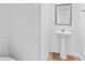 Simple powder room with a pedestal sink, decorative mirror, and hardwood floors at 3660 Cattle Field Xing, Loganville, GA 30052