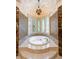 Bright bathroom featuring a jacuzzi tub beneath stained glass windows and a decorative chandelier at 720 Heards Ferry Rd, Sandy Springs, GA 30328