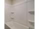 Clean white bathtub and shower with built-in shelving for toiletries at 1816 Kingsmere Run Dr, Loganville, GA 30052