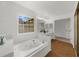 Bright bathroom showcasing soaking tub, vanity with dual mirrors, and tile floor at 11660 Windbrooke Way, Johns Creek, GA 30005