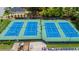 Close up of four blue tennis courts with lights, landscaping, seating, and community signage on the fencing at 11660 Windbrooke Way, Johns Creek, GA 30005