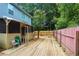 Cozy backyard features a spacious wooden deck, pink fencing, screened-in porch, and mature trees offering shade at 2468 Whistle Stop Dr, Norcross, GA 30071