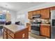 Kitchen featuring stainless steel appliances, wood cabinets, tile backsplash, and an island with a view to the dining area at 2468 Whistle Stop Dr, Norcross, GA 30071