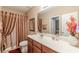 Bathroom with cherry vanity, cultured marble countertop, decorative vase, and framed mirror at 3202 Lucky Pl, Conyers, GA 30013