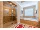 Bright bathroom boasting a glass enclosed shower, soaking tub with tile, and neutral color palette at 3202 Lucky Pl, Conyers, GA 30013