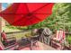 View of the deck featuring a red umbrella, table, chairs, and a grill overlooking a wooded area at 3202 Lucky Pl, Conyers, GA 30013