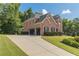 Long driveway leading to a brick home with an attached two-car garage and lush greenery at 3202 Lucky Pl, Conyers, GA 30013