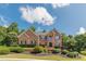 Beautiful brick home featuring mature landscaping and manicured lawn under a bright blue sky at 3202 Lucky Pl, Conyers, GA 30013