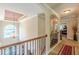 Bright hallway featuring hardwood railing, columns, arched doorways, and decorative lighting fixture at 3202 Lucky Pl, Conyers, GA 30013