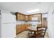 Kitchen with wood cabinets, white appliances, and an eat-in dining table at 3355 Old Peachtree Rd, Dacula, GA 30019