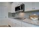 Close-up view of modern kitchen with stainless steel microwave, granite countertops, and gray subway tile backsplash at 1797 Kingsmere Run Dr, Loganville, GA 30052