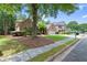 Sidewalk view of brick house with green lawn, two car garage, and side yard featuring mature trees at 1065 Beacon Hill Xing, Alpharetta, GA 30005