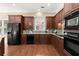 Kitchen with stainless appliances, dark wood cabinetry, granite counters, and hardwood floors at 1065 Beacon Hill Xing, Alpharetta, GA 30005