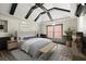 Staged main bedroom featuring ceiling beams, ceiling fan, and accent wall at 1065 Beacon Hill Xing, Alpharetta, GA 30005