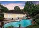 Gorgeous kidney-shaped pool and spa with brick surround, patio, and manicured landscaping at twilight at 1065 Beacon Hill Xing, Alpharetta, GA 30005