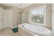 Bright bathroom featuring a soaking tub with tile surround and glass shower at 2444 Mossy Branch Dr, Snellville, GA 30078