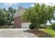 Exterior image showcasing the garage and driveway, enhanced by lush landscaping at 2444 Mossy Branch Dr, Snellville, GA 30078