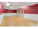 Finished basement with wood flooring, bright lighting, and red accent wall at 3105 Sumac Dr, Atlanta, GA 30360