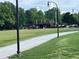 Expansive green space with walking path, bordered by trees, street lights, and with park structures in the distance at 4876 Velva Nw Way, Lilburn, GA 30047