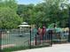 Community playground with modern equipment and a gazebo, surrounded by lush greenery and a secure fence at 4876 Velva Nw Way, Lilburn, GA 30047