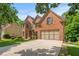 Attractive brick house with a large driveway and attached two-car garage, set against a lush green backdrop at 1170 Shellnut Trl, Hoschton, GA 30548