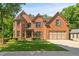 Elegant brick home with a well-manicured lawn, lush greenery, and attached two-car garage at 1170 Shellnut Trl, Hoschton, GA 30548
