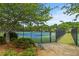 View of fenced community tennis courts with green lawn, mature trees, and manicured bushes at 1170 Shellnut Trl, Hoschton, GA 30548